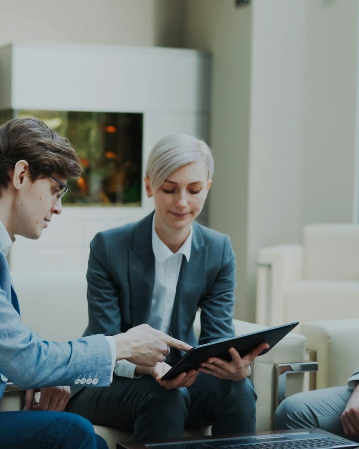 An adviser reviewing figures on a tablet with a client in a light-filled office