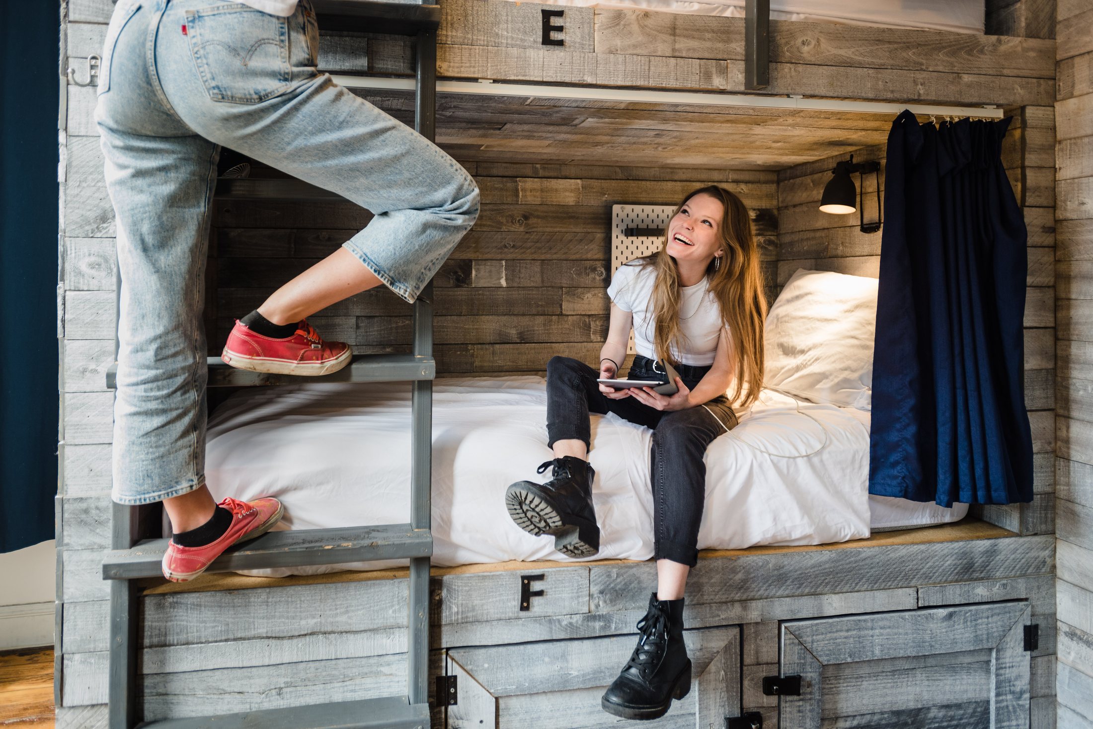 Two guests at a custom timber bunk in a hostel dorm