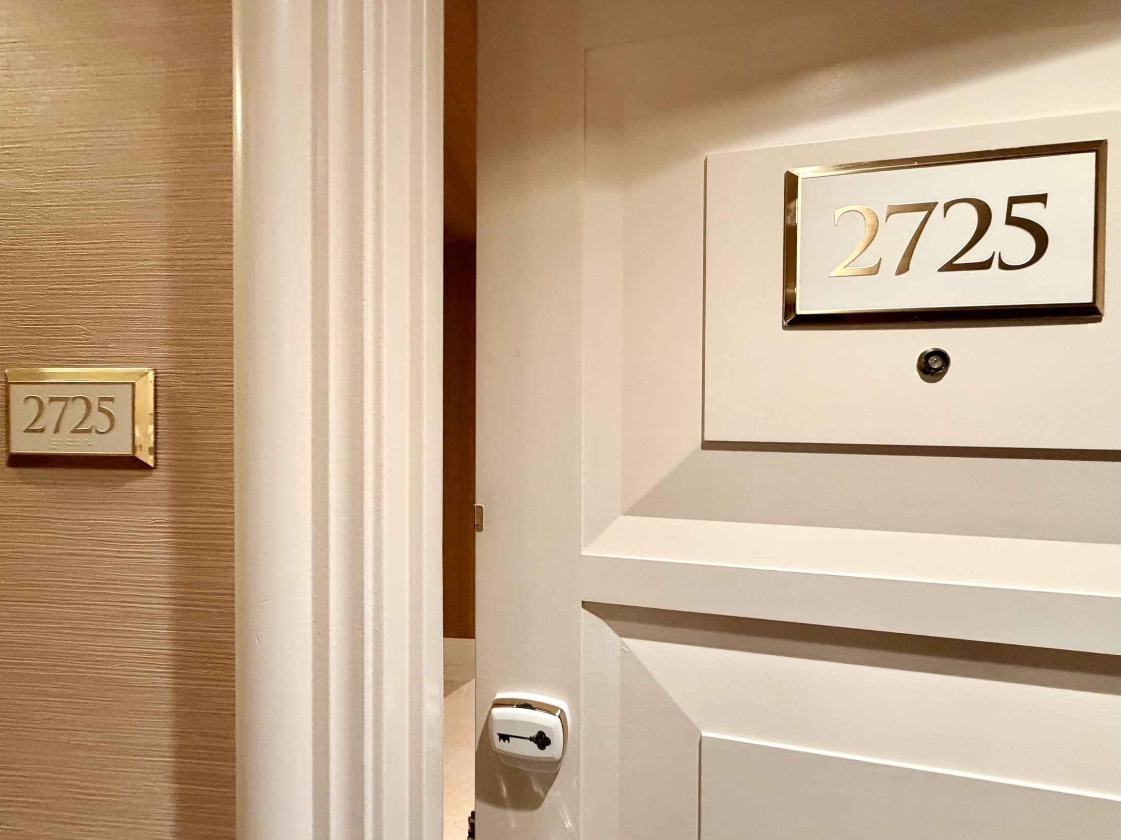 A hotel room door with a brass plaque reading 2725